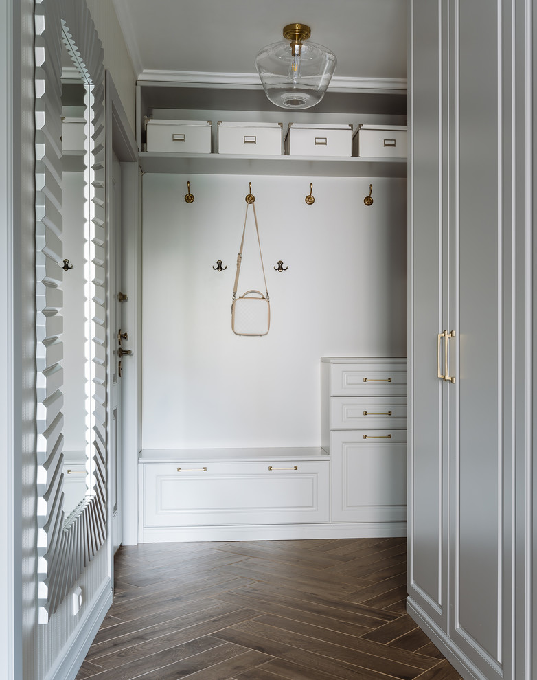Стильный дизайн: узкая прихожая среднего размера в стиле неоклассика (современная классика) с серыми стенами, полом из керамогранита, одностворчатой входной дверью, серой входной дверью и коричневым полом - последний тренд