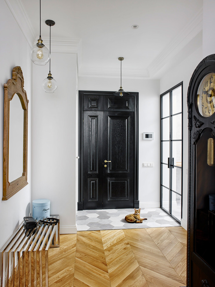 Diseño de puerta principal bohemia con paredes blancas, suelo de madera clara, puerta negra y puerta simple