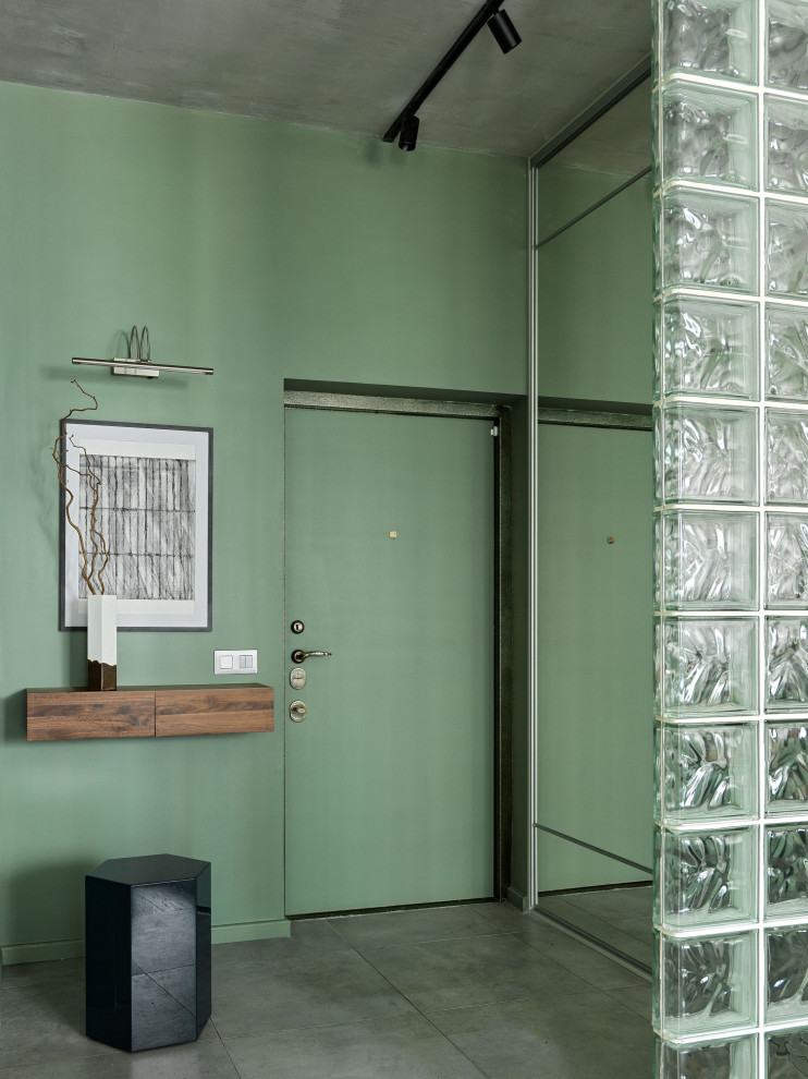 Immagine di un piccolo corridoio design con pareti verdi, pavimento in gres porcellanato, una porta singola, una porta verde e pavimento grigio