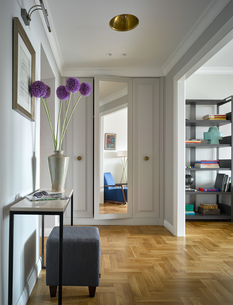 Example of a transitional medium tone wood floor entryway design in Moscow with white walls