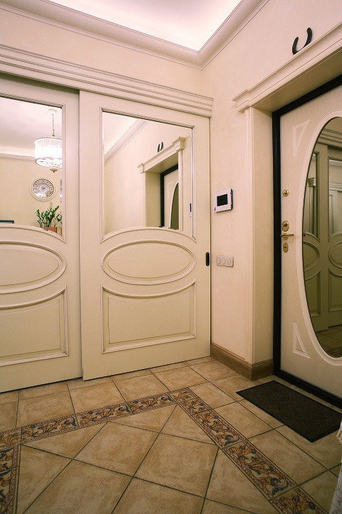 Cette image montre une porte d'entrée traditionnelle de taille moyenne avec un mur beige, un sol en carrelage de céramique, une porte simple, une porte en bois clair et un sol beige.