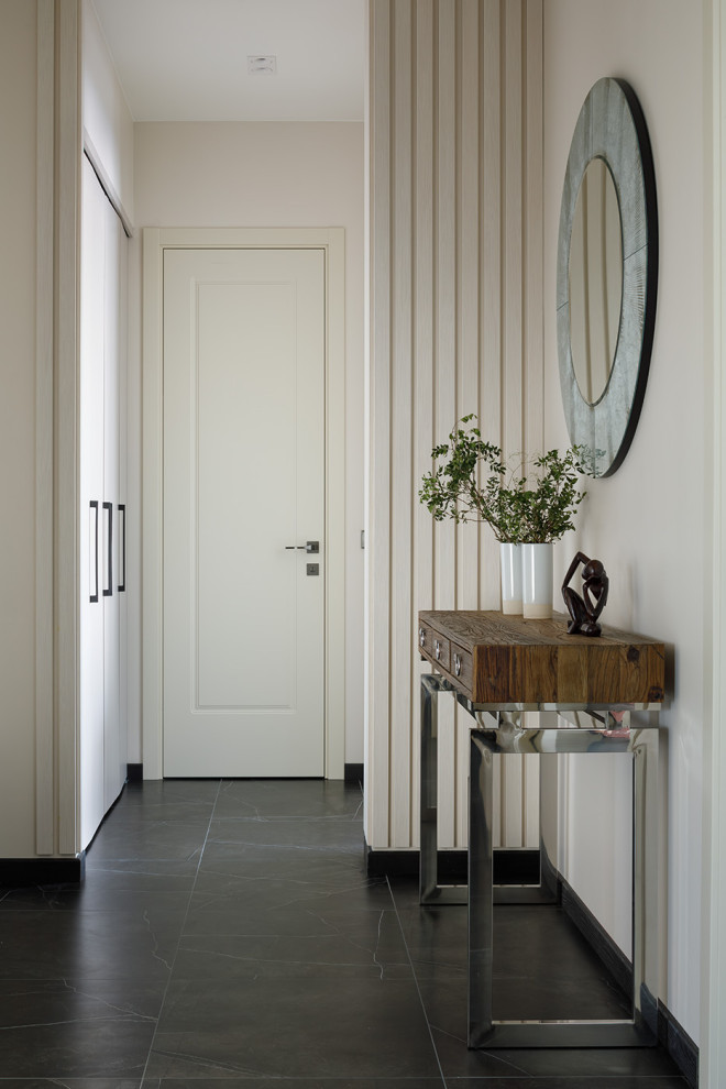 Foto di un ingresso con vestibolo minimal di medie dimensioni con pareti beige, pavimento in gres porcellanato, una porta singola, pavimento nero, soffitto ribassato e pannellatura