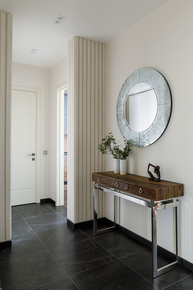 Ejemplo de vestíbulo contemporáneo de tamaño medio con paredes beige, suelo de baldosas de porcelana, puerta simple, suelo negro, bandeja y panelado