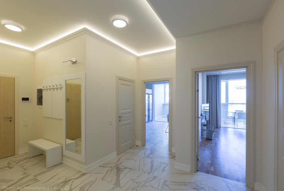 Ispirazione per un grande corridoio contemporaneo con pareti beige, pavimento in gres porcellanato, una porta in legno bruno e pavimento bianco