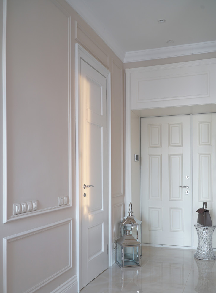 На фото: входная дверь в стиле неоклассика (современная классика) с бежевыми стенами, двустворчатой входной дверью, белой входной дверью и бежевым полом с