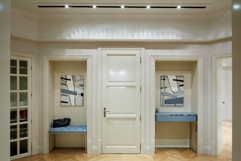 Aménagement d'une entrée classique avec un mur blanc, parquet clair, une porte simple et une porte blanche.