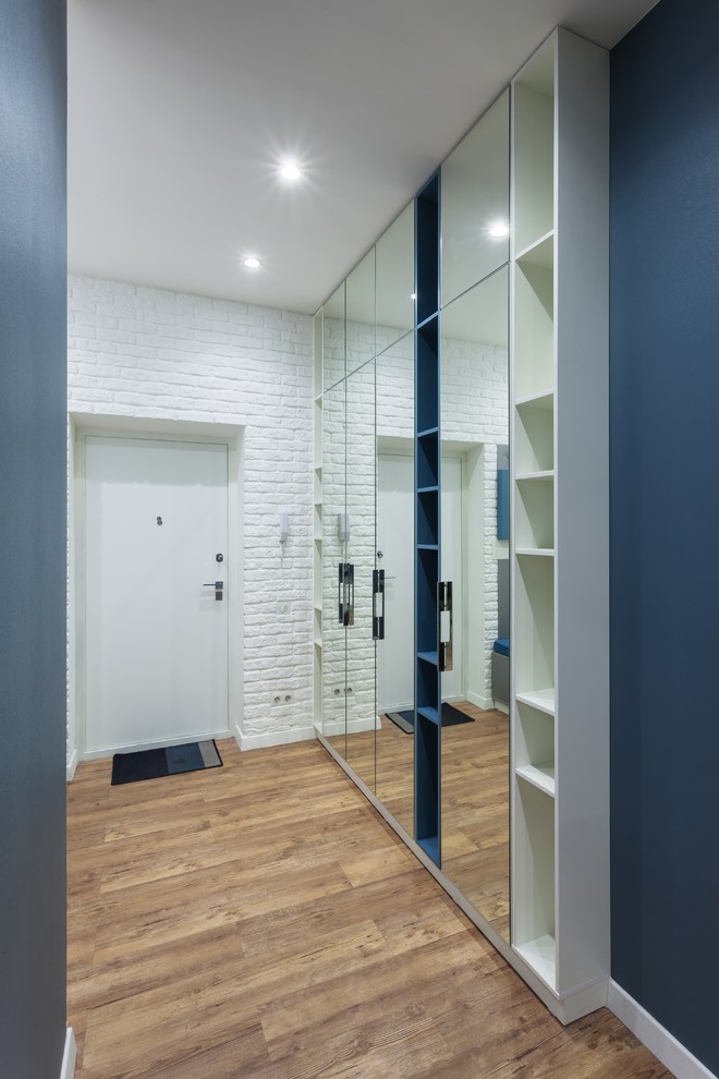 Idéer för en mellanstor modern ingång och ytterdörr, med blå väggar, en enkeldörr, en vit dörr och brunt golv