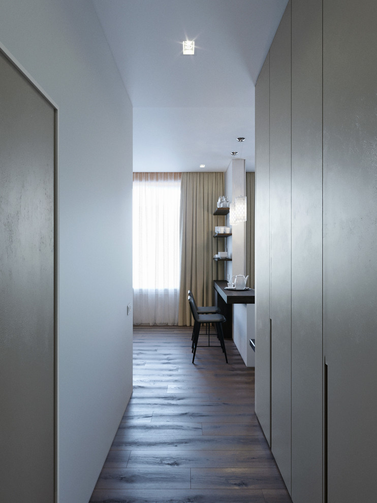 Cette photo montre une petite entrée tendance avec un couloir, sol en stratifié, un sol marron et un mur beige.