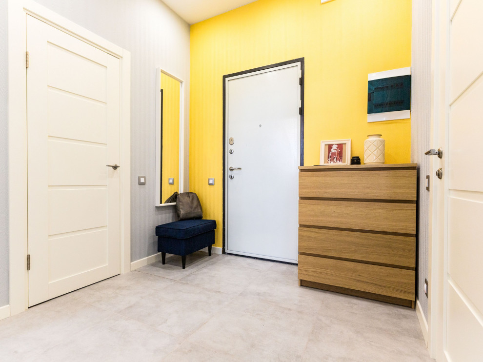 Foto di un ingresso con vestibolo di medie dimensioni con pareti gialle, pavimento in gres porcellanato, una porta in metallo e carta da parati