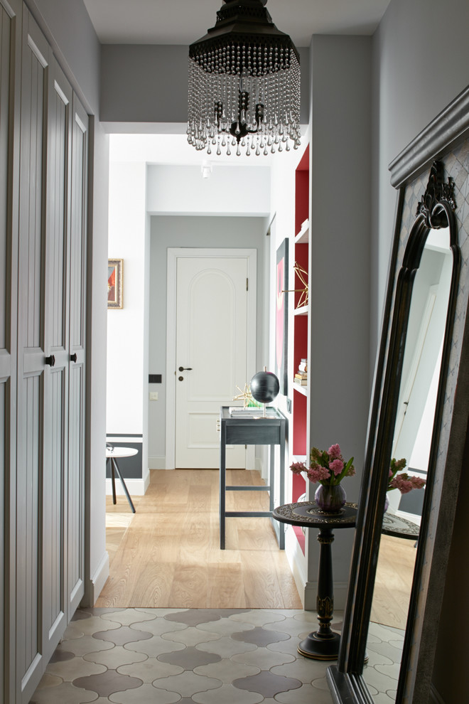 На фото: узкая прихожая в стиле неоклассика (современная классика) с серыми стенами и полом из керамической плитки с