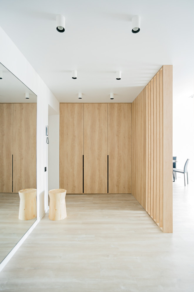 Cette image montre un hall d'entrée design avec un mur blanc et un sol beige.