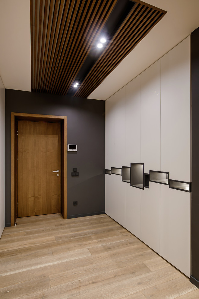 На фото: входная дверь среднего размера в современном стиле с серыми стенами, паркетным полом среднего тона, одностворчатой входной дверью, входной дверью из дерева среднего тона и бежевым полом с
