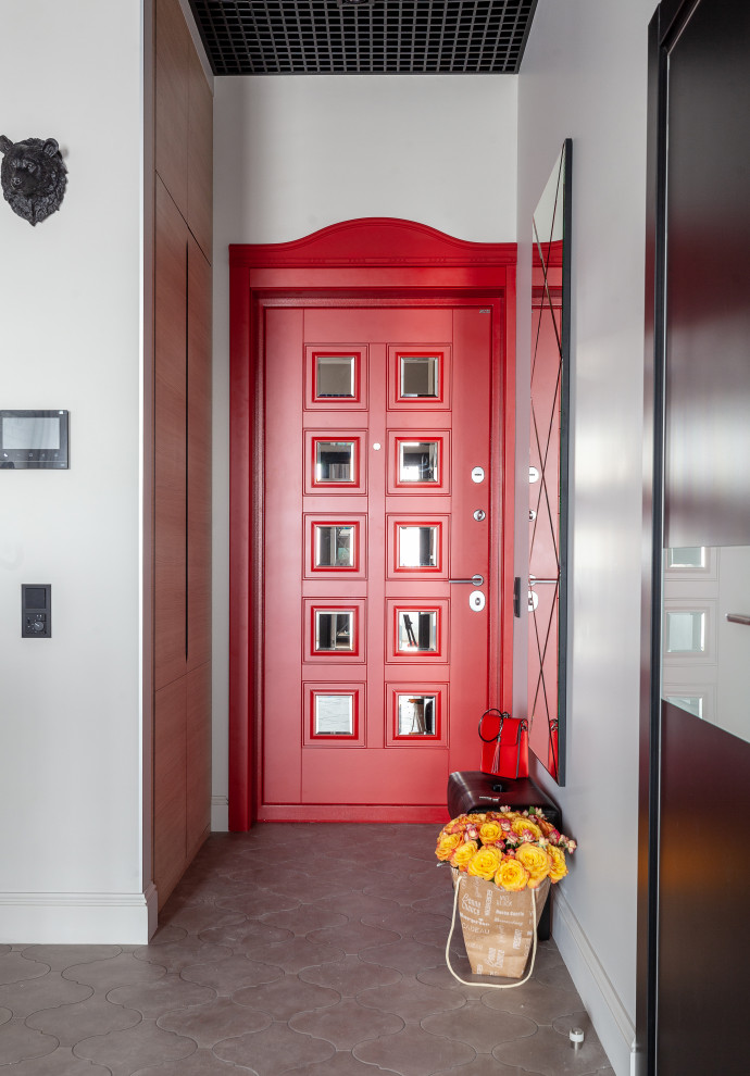 Cette image montre une petite porte d'entrée urbaine avec un mur gris, un sol en carrelage de céramique, une porte simple, une porte rouge et un sol gris.