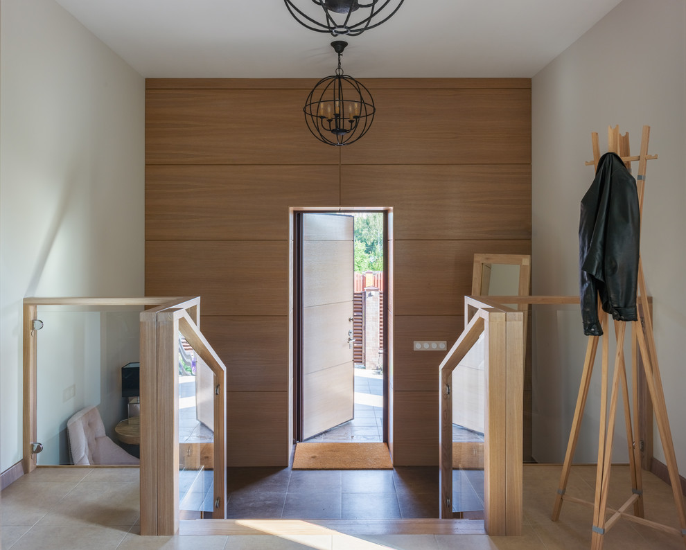 Modelo de puerta principal actual con paredes blancas, puerta simple, puerta de madera clara y suelo marrón