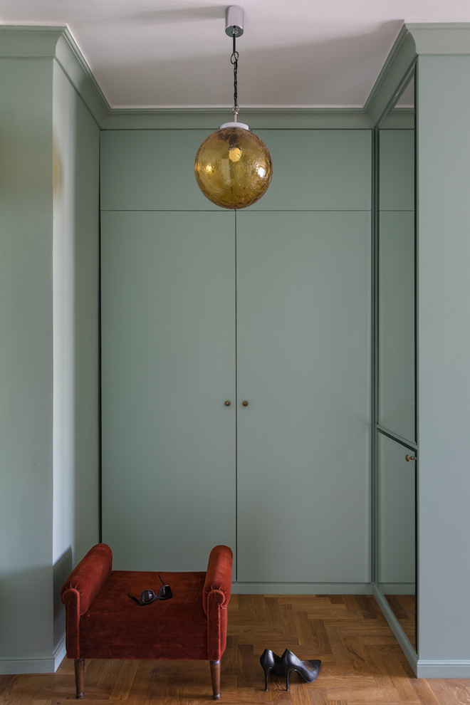 Idée de décoration pour une petite entrée design avec un vestiaire, un mur vert et un sol en bois brun.