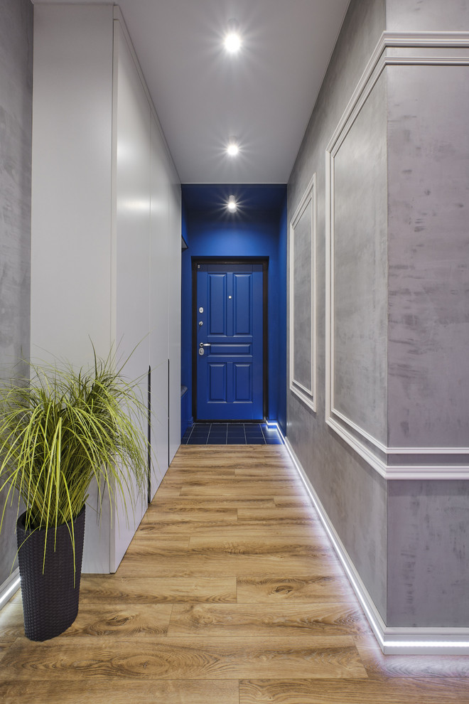 Réalisation d'une petite porte d'entrée urbaine avec un mur gris, sol en stratifié, une porte simple, une porte bleue et un sol beige.