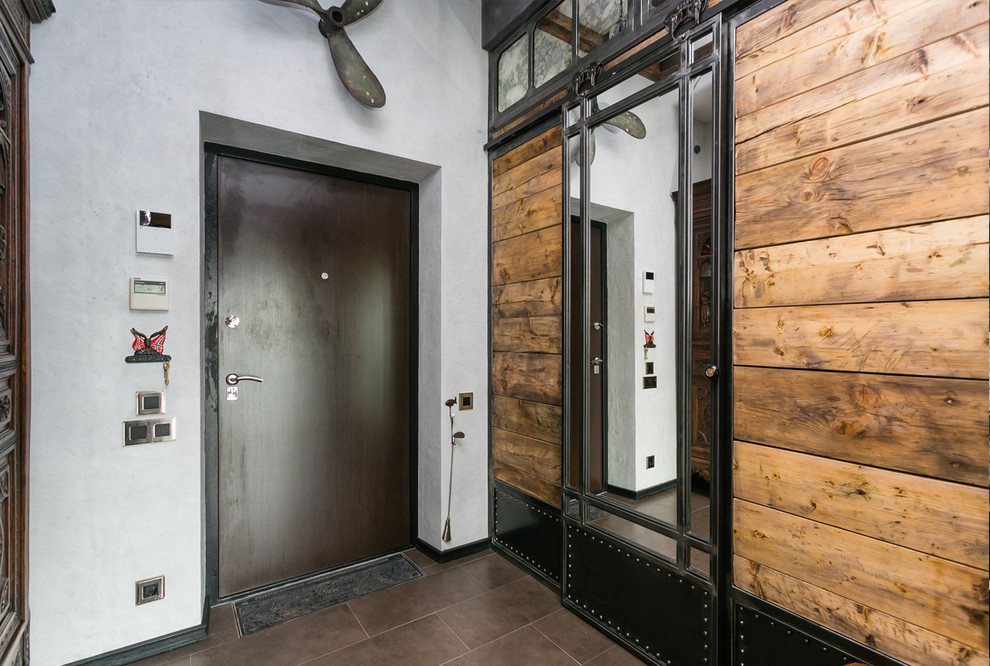 На фото: входная дверь среднего размера в стиле лофт с серыми стенами, полом из керамогранита, одностворчатой входной дверью, входной дверью из темного дерева и коричневым полом с