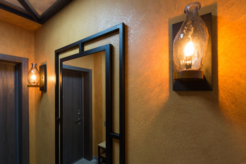 他の地域にあるお手頃価格の中くらいなインダストリアルスタイルのおしゃれな玄関ドア (オレンジの壁、セラミックタイルの床、グレーのドア、グレーの床) の写真