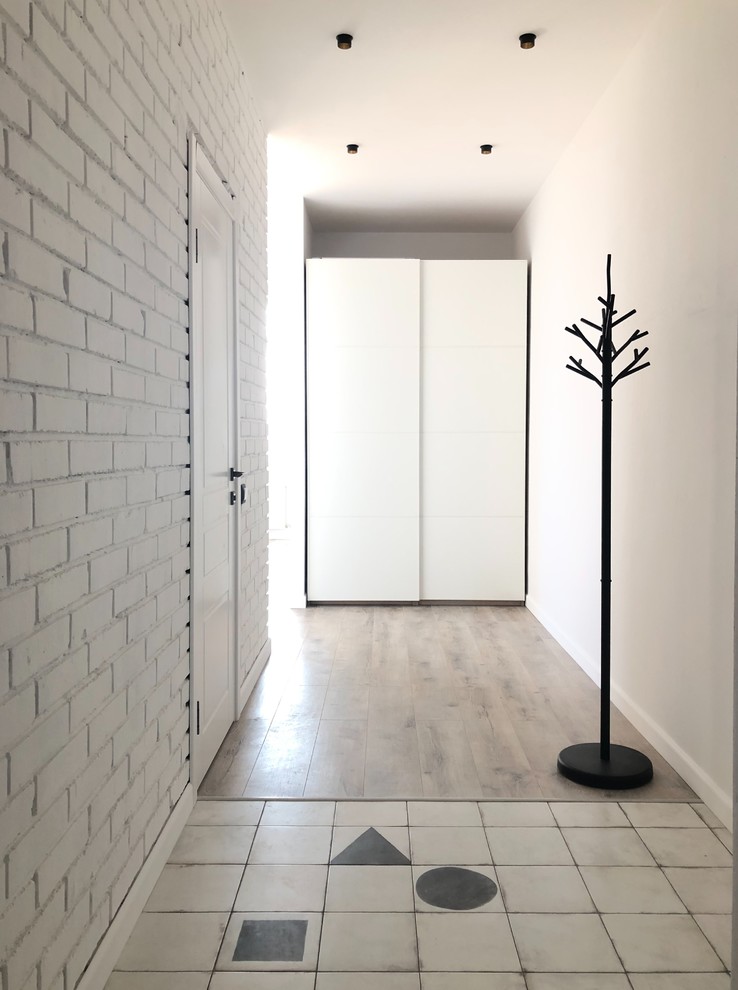 他の地域にある低価格の中くらいなコンテンポラリースタイルのおしゃれな玄関ホール (白い壁、セラミックタイルの床、白い床) の写真