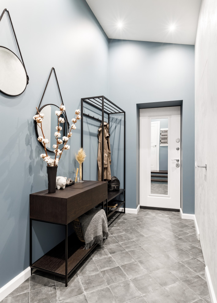 Idée de décoration pour une entrée design de taille moyenne avec un vestiaire, un mur bleu, un sol en carrelage de porcelaine, une porte simple, une porte blanche, un sol gris et du papier peint.