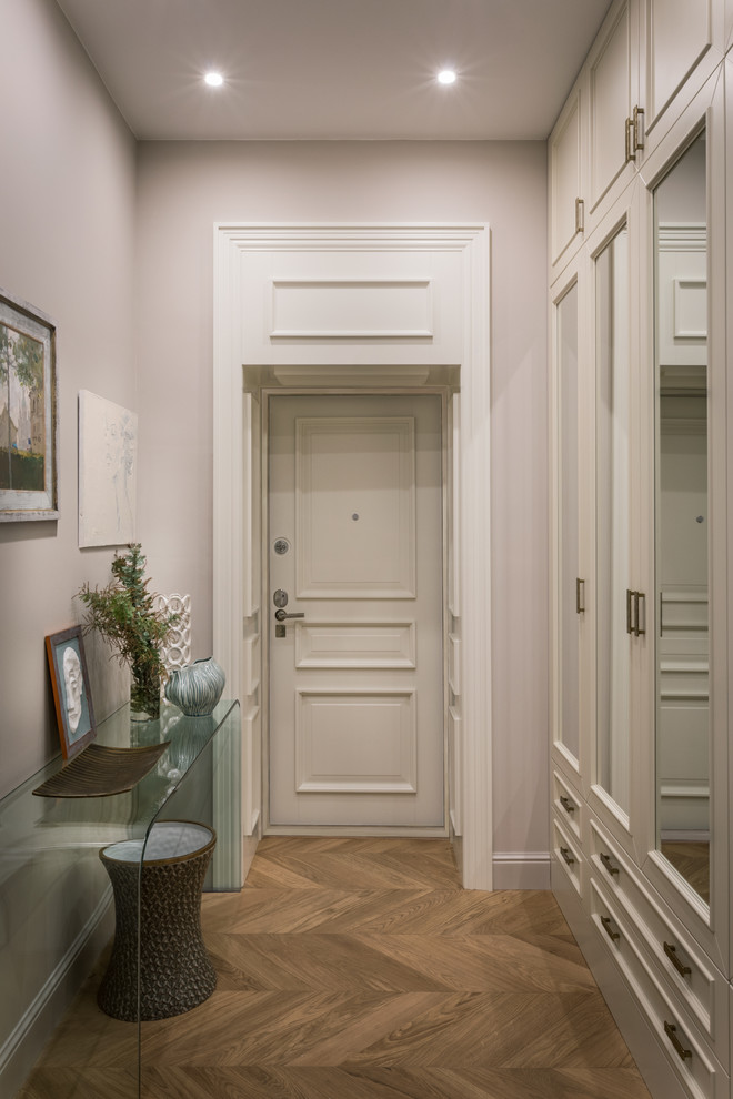 Ispirazione per un corridoio chic con pavimento in legno massello medio, una porta singola, una porta bianca, pavimento marrone e pareti grigie