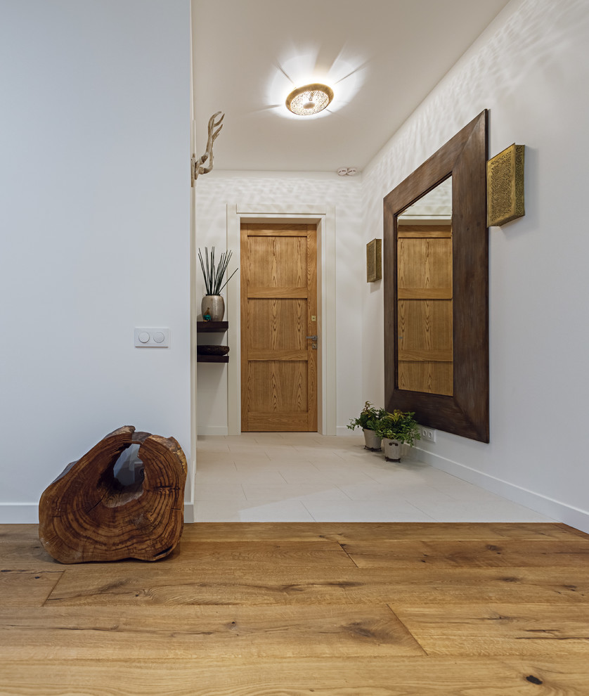 На фото: входная дверь в современном стиле с белыми стенами, одностворчатой входной дверью и входной дверью из дерева среднего тона с