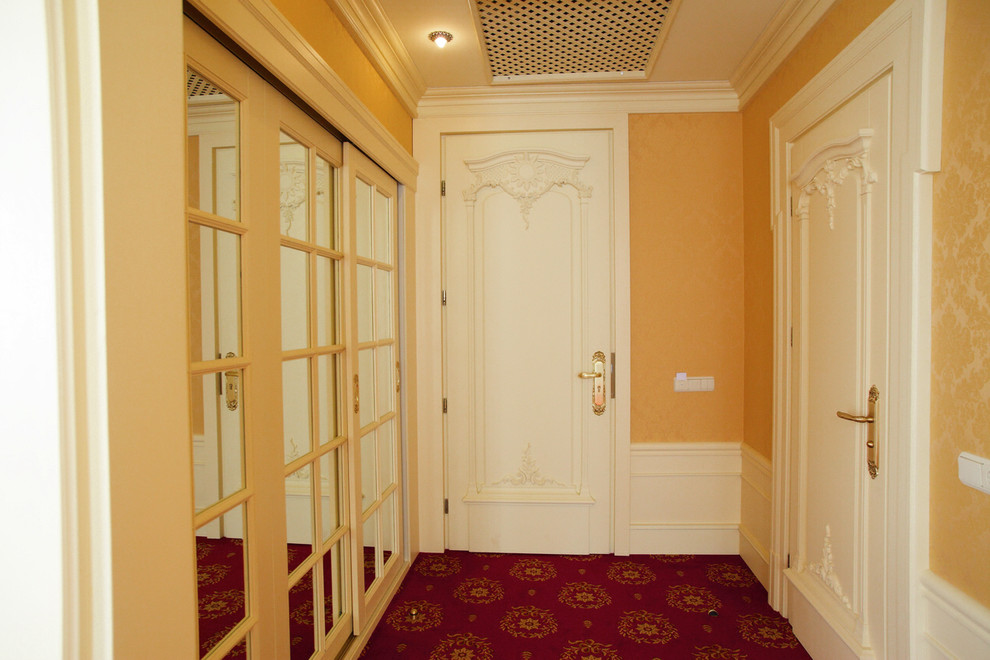 На фото: входная дверь в классическом стиле с бежевыми стенами, ковровым покрытием, белой входной дверью и красным полом