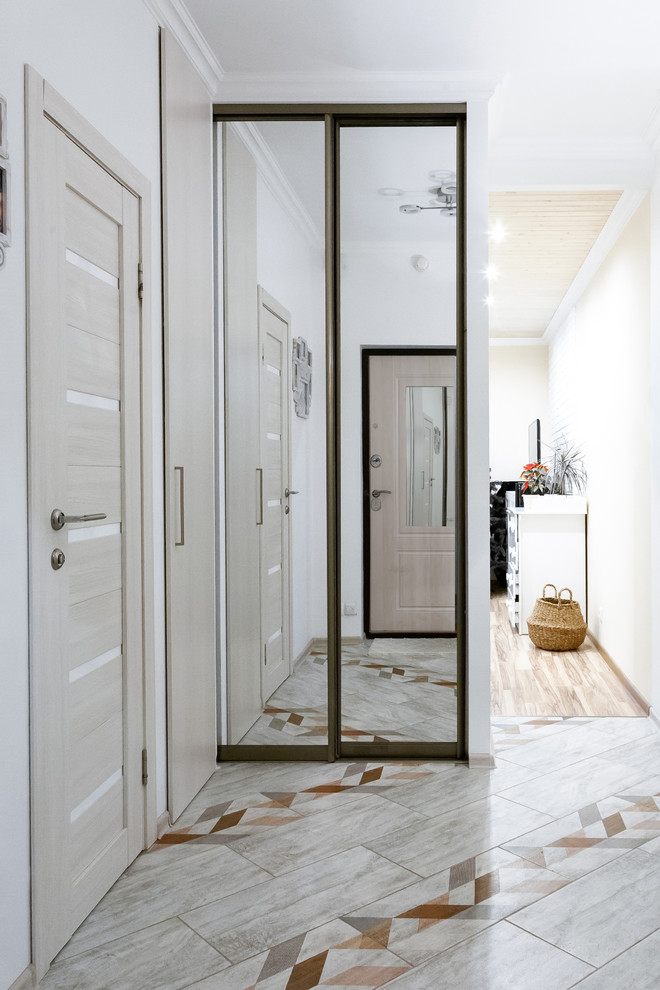 Ispirazione per un piccolo corridoio nordico con pareti bianche, pavimento in gres porcellanato, una porta singola, una porta in legno chiaro e pavimento beige