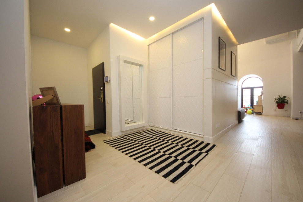 Стильный дизайн: узкая прихожая среднего размера в современном стиле с белыми стенами, полом из керамогранита, голландской входной дверью, коричневой входной дверью, белым полом и обоями на стенах - последний тренд
