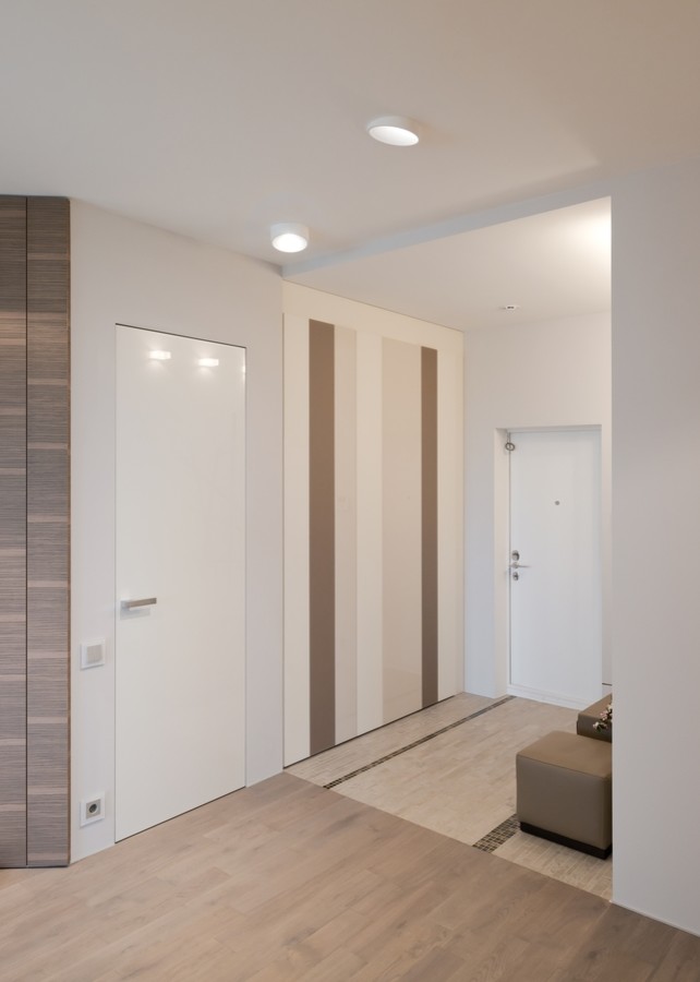 Inspiration pour une petite entrée design avec un vestiaire, un mur beige, un sol en bois brun, une porte simple, une porte blanche et un sol beige.