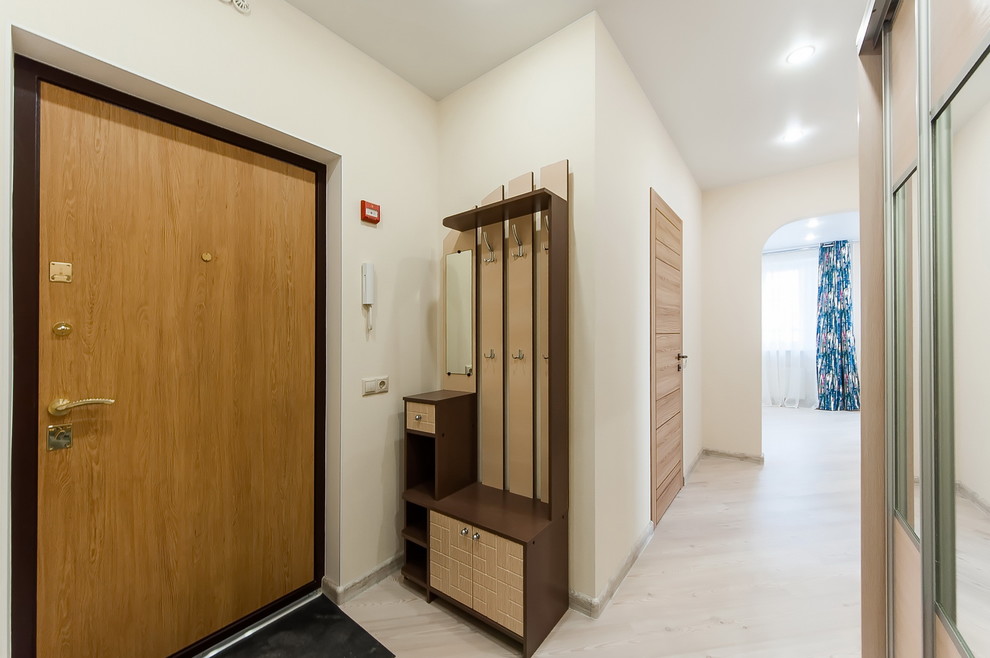 This is an example of a medium sized scandi hallway in Moscow with beige walls, laminate floors, a single front door, a medium wood front door and beige floors.