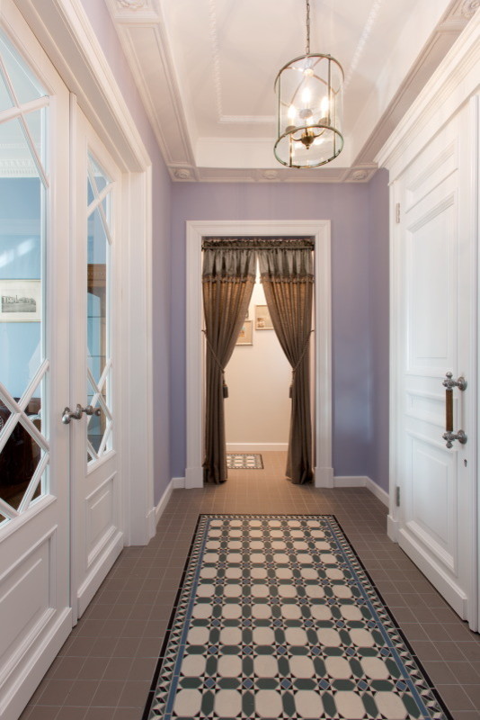 Стильный дизайн: узкая прихожая в классическом стиле с фиолетовыми стенами, полом из керамогранита и белой входной дверью - последний тренд