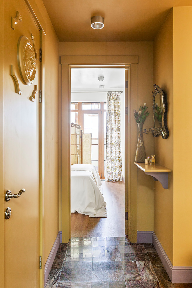 Eklektisk inredning av en liten hall, med gula väggar, marmorgolv, brunt golv och en enkeldörr