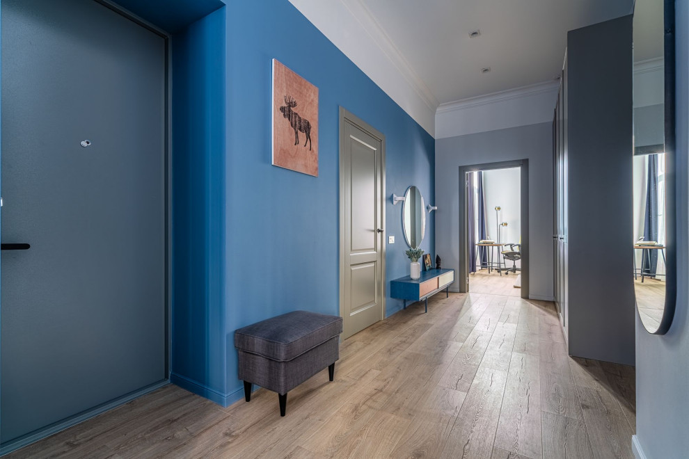 На фото: маленькая входная дверь в скандинавском стиле с синими стенами, полом из ламината, одностворчатой входной дверью, синей входной дверью, коричневым полом, многоуровневым потолком и обоями на стенах для на участке и в саду