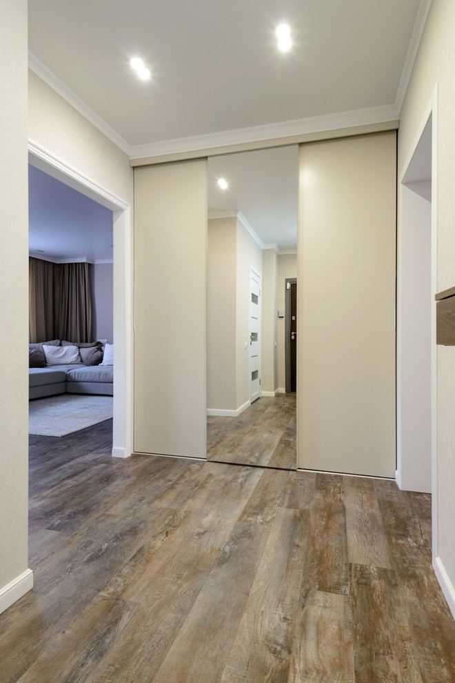 Diseño de hall contemporáneo de tamaño medio con paredes beige, suelo vinílico, puerta simple, puerta marrón y suelo marrón
