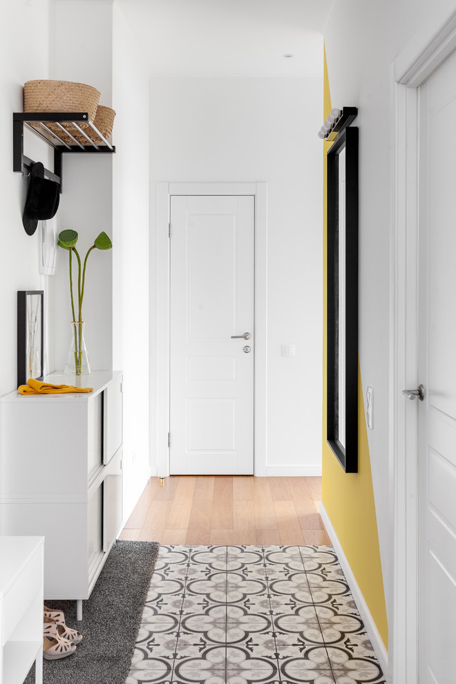Inredning av en minimalistisk hall, med vita väggar, klinkergolv i keramik, en enkeldörr, en vit dörr och flerfärgat golv