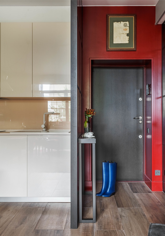 Свежая идея для дизайна: входная дверь в современном стиле с красными стенами, паркетным полом среднего тона, одностворчатой входной дверью, черной входной дверью и коричневым полом - отличное фото интерьера