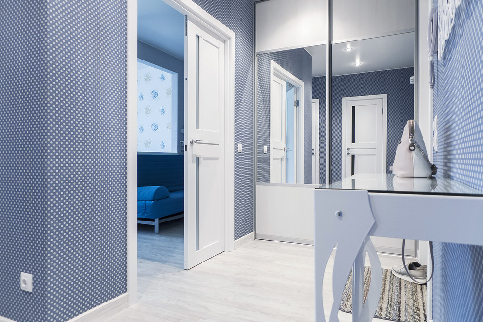 Inredning av en modern mellanstor hall, med blå väggar, vinylgolv, en enkeldörr, en vit dörr och grått golv