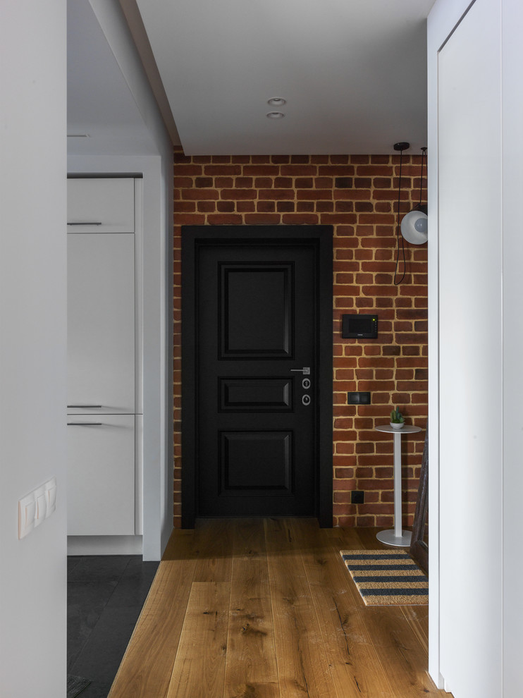 Свежая идея для дизайна: входная дверь в стиле лофт с коричневыми стенами, паркетным полом среднего тона, одностворчатой входной дверью, черной входной дверью и коричневым полом - отличное фото интерьера