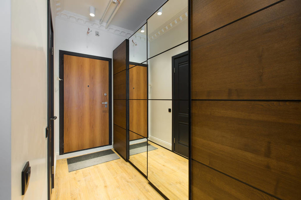 Réalisation d'une entrée design avec un mur blanc, une porte simple et une porte en bois brun.