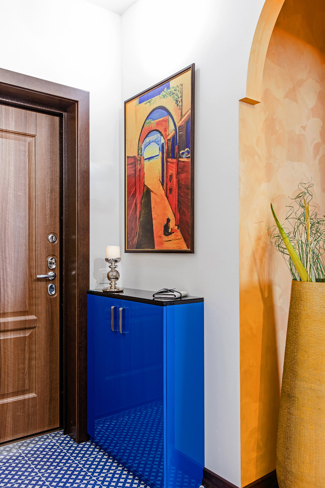 Cette photo montre une porte d'entrée éclectique avec un mur blanc, une porte simple, une porte en bois brun et un sol bleu.