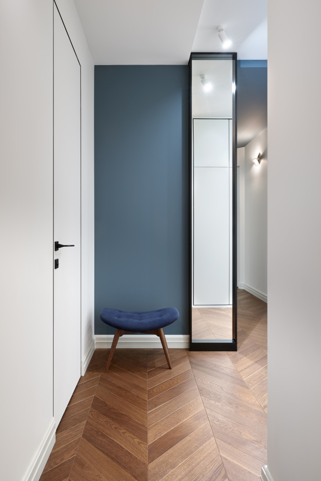 Kleiner Moderner Eingang mit Korridor, blauer Wandfarbe, braunem Holzboden und eingelassener Decke in Moskau