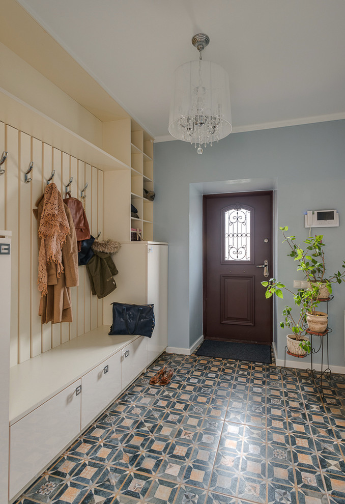 Idée de décoration pour une grande porte d'entrée bohème avec un mur bleu, une porte simple, une porte marron et un sol multicolore.