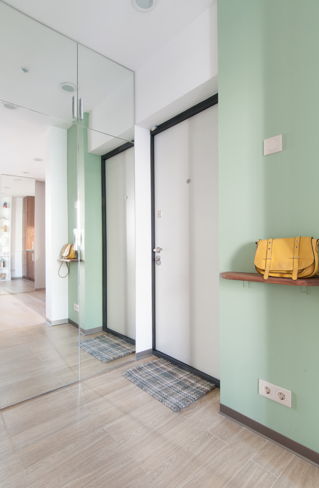 Diseño de puerta principal contemporánea con paredes verdes, suelo de madera clara, puerta simple y puerta blanca