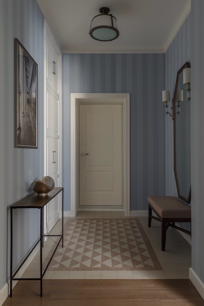 Idee per un corridoio chic con pareti blu, pavimento beige, una porta singola e una porta bianca