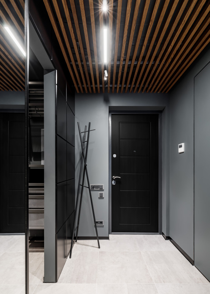 Cette photo montre une porte d'entrée tendance de taille moyenne avec un mur gris, une porte simple, une porte noire, un sol beige et un plafond en bois.