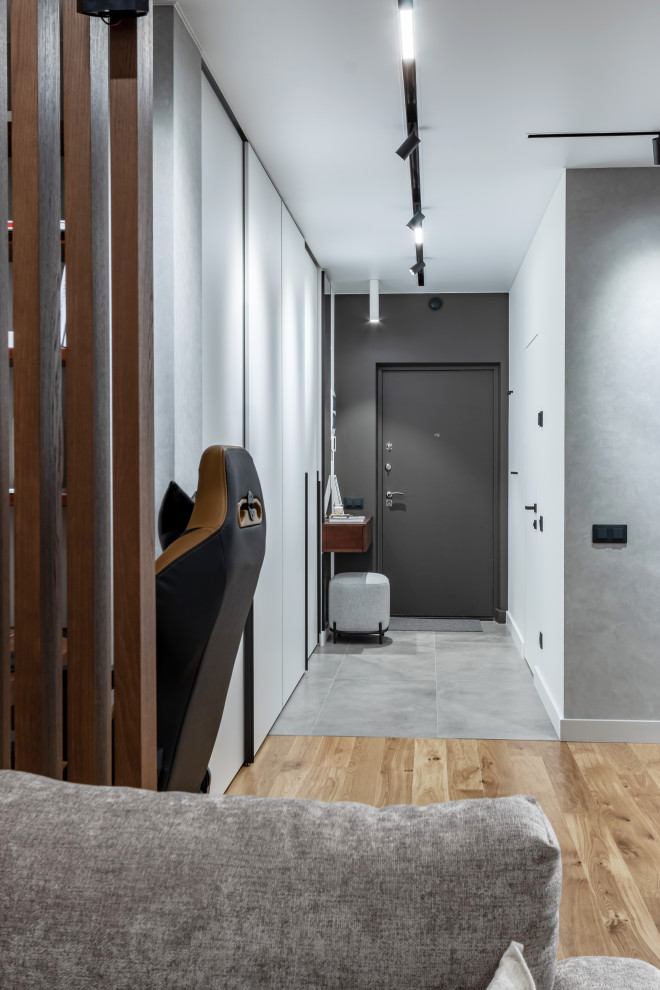 Exemple d'une petite entrée tendance avec un couloir, un mur blanc, un sol en carrelage de porcelaine, une porte simple, une porte noire et un sol gris.