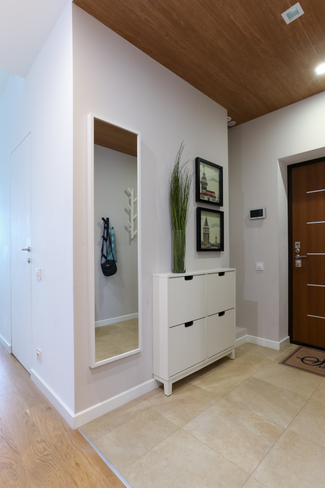 Идея дизайна: маленькая входная дверь в современном стиле с белыми стенами, полом из керамогранита, одностворчатой входной дверью, входной дверью из дерева среднего тона и бежевым полом для на участке и в саду