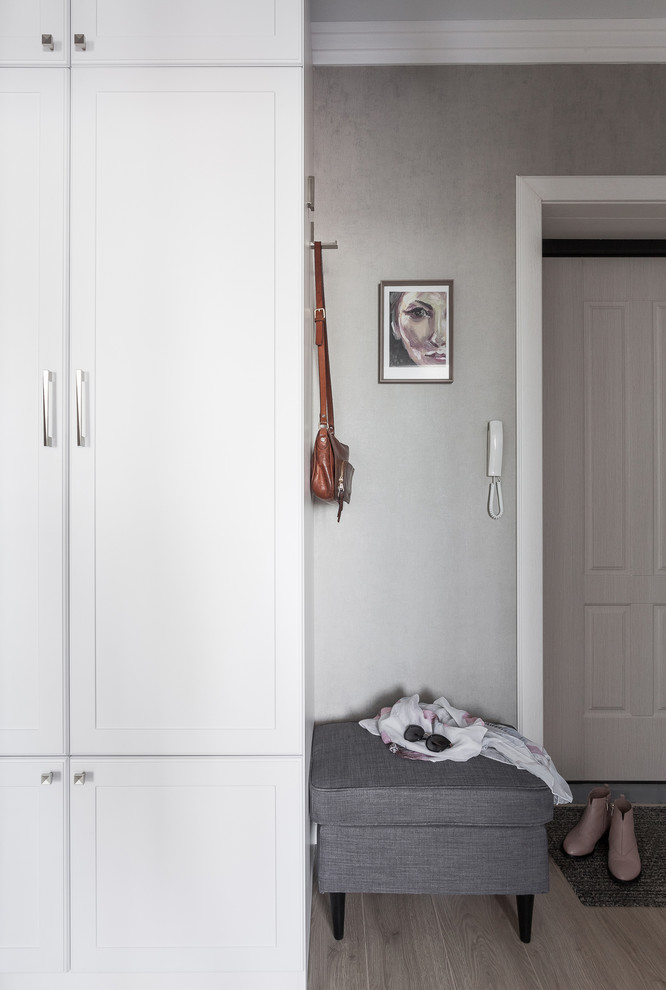 Réalisation d'une petite porte d'entrée tradition avec un mur gris, sol en stratifié, une porte simple, une porte en bois clair et un sol beige.