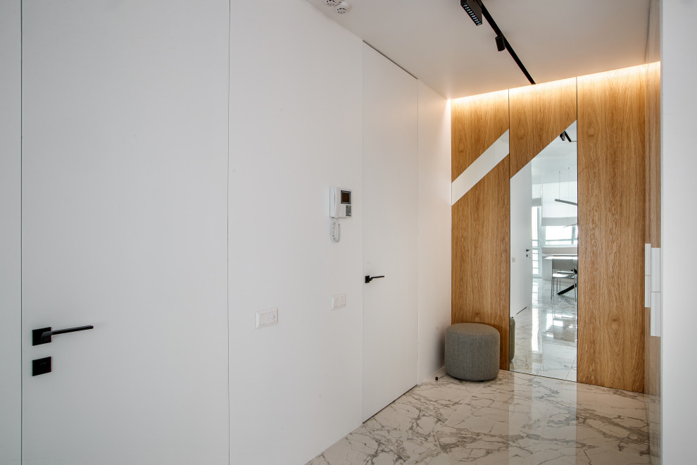 Modelo de hall contemporáneo grande con paredes blancas, suelo gris, puerta simple y puerta blanca